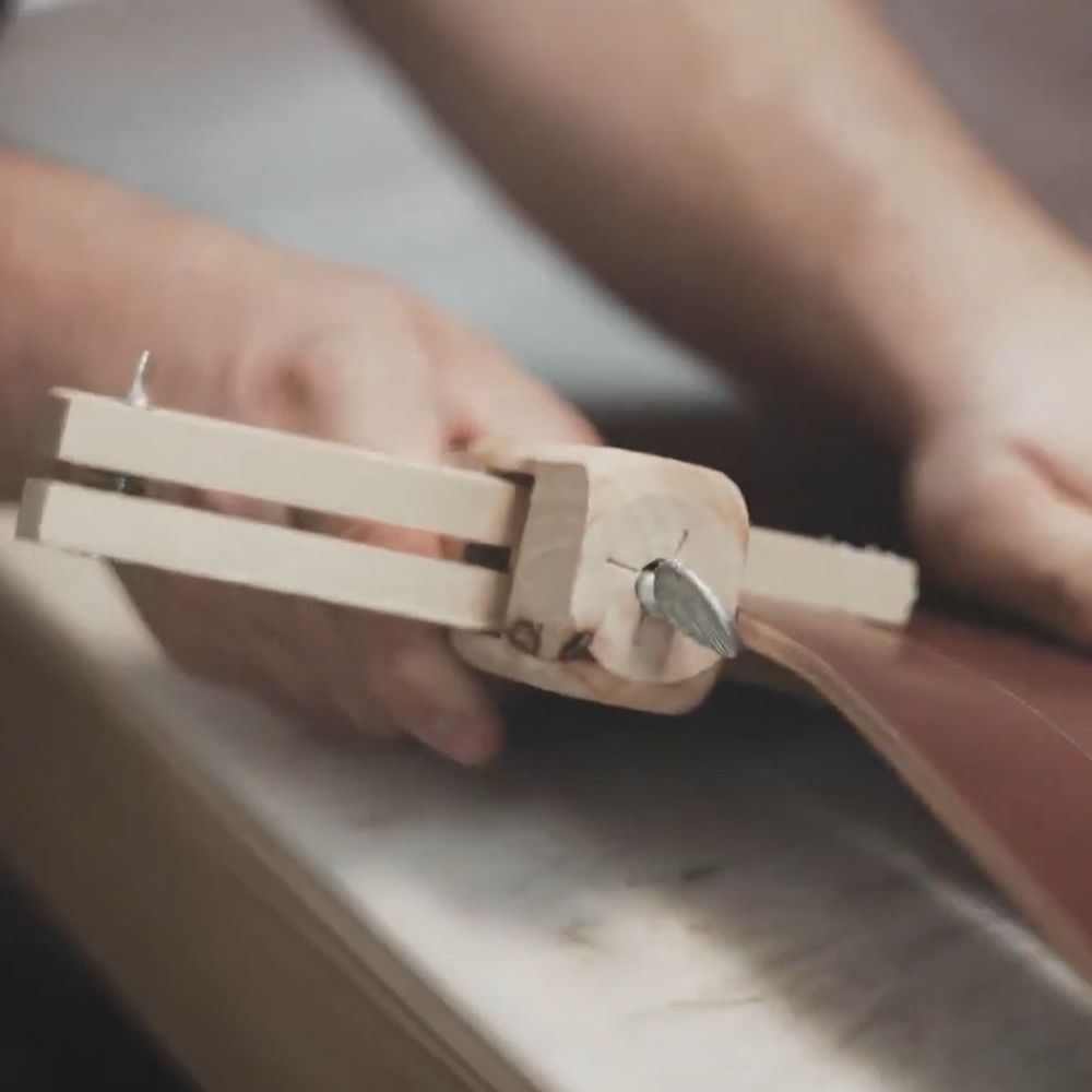 The maker marking a leather strap with a wooden gauge